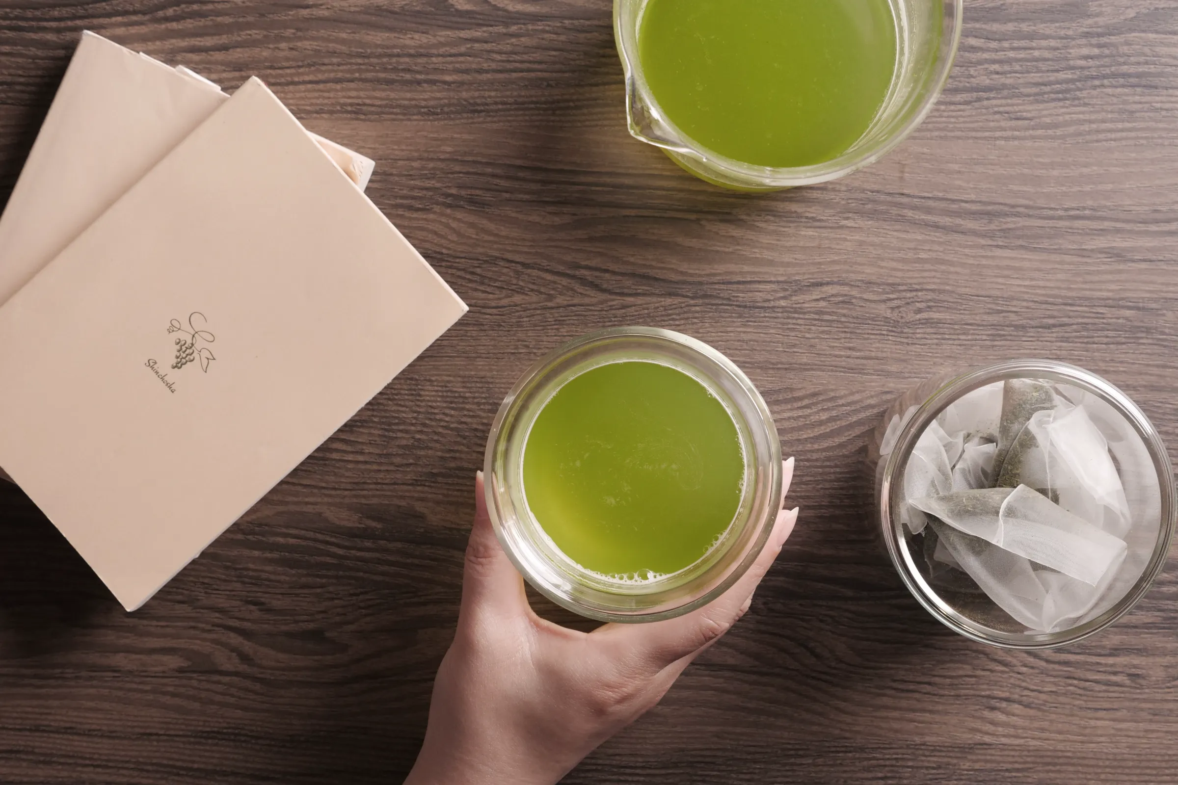 木のテーブルに置かれた抹茶色のお茶とティーバッグ